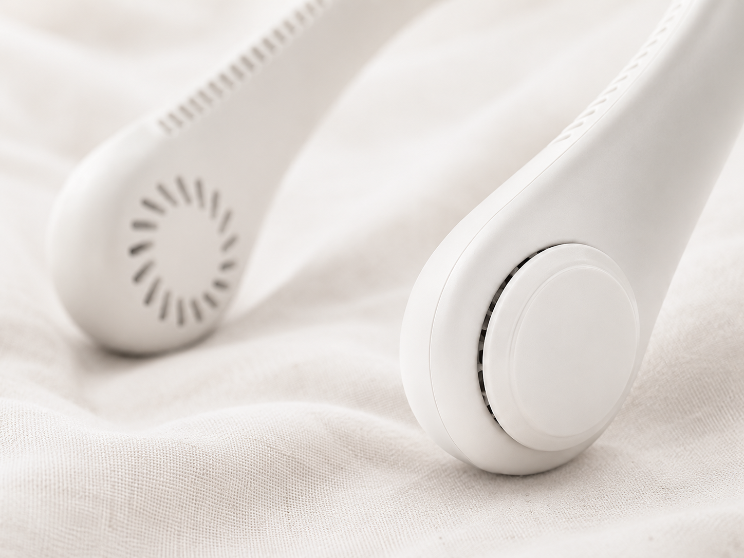 Close-up detail of BreezeLoop neck fan pods showing air intake grilles and soft silicone construction on linen fabric